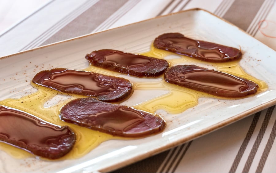 A rectangle plate with slices of dry-aged tuna loin drizzled with Spanish olive oil