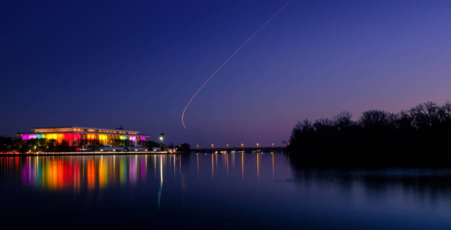 View of the Kennedy Center illuminated at night and reflected on the Potomac River