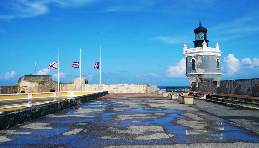 View of the lighthouse in El Morro and three different flags on the poles