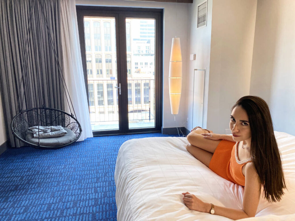 Clara Kesseler sitting on a bed in The Maven, one of the best hotels in Denver