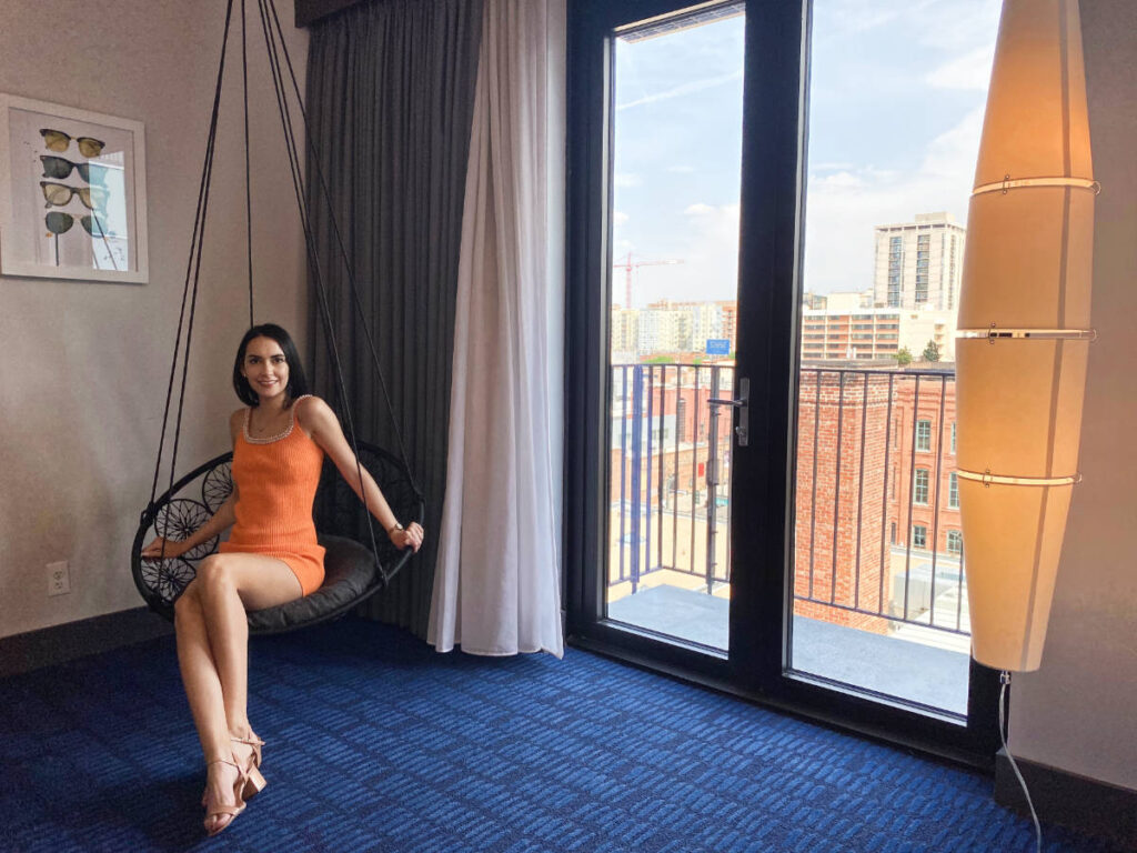 Clara Kesseler sitting inside their room with a balcony view in The Maven Hotel Denver