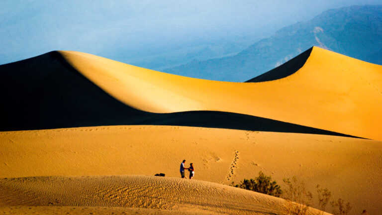 Two people standing on the sand dune at The Mesquite Flat Dunes