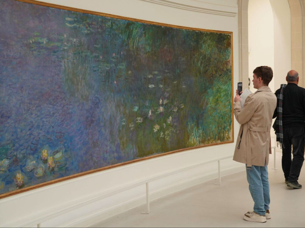 Visitor taking a photo at the Monet lilies exhibit in Musée de L’Orangerie
