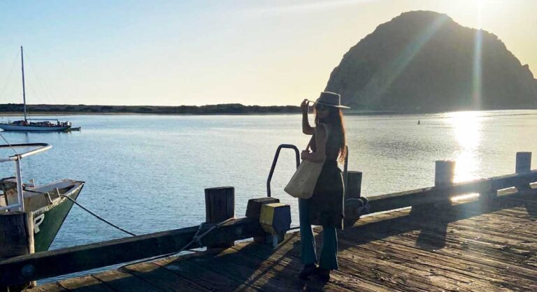 The author McKenna Mobley posing for a photo with the Morro Rock on her background