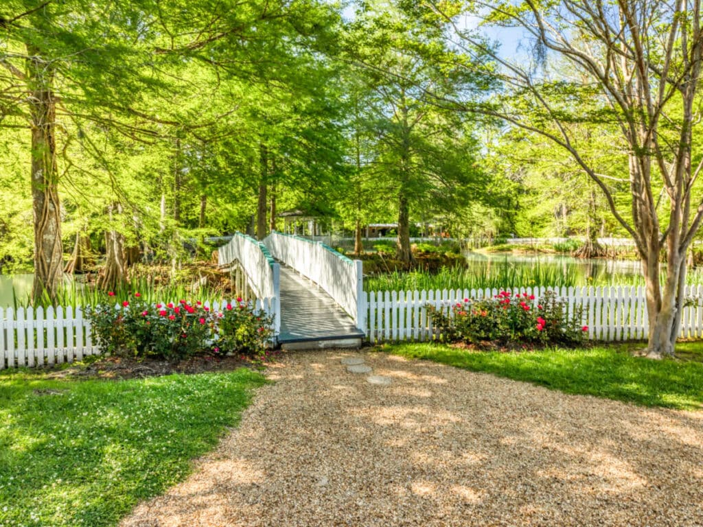 View of the bridge surrounded with a white fence and greenery in The Myrtles Plantation