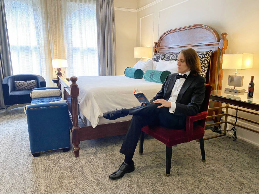 The author, Nate Hake reading a book in a chair in a room at the Oxford Hotel