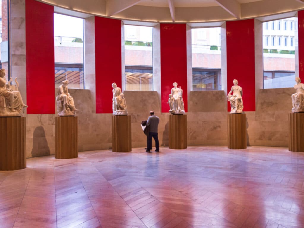 A man looking at the statues in Prado Museum
