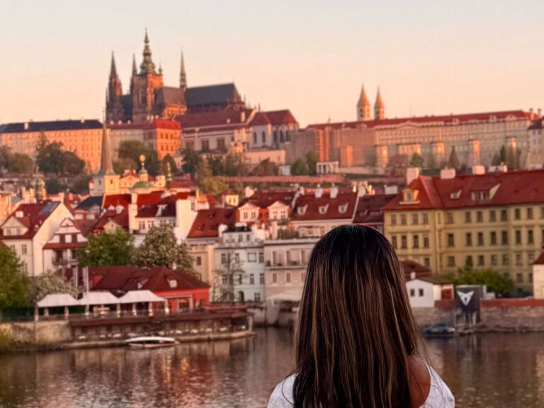 Author Meera looking at the view of the Prague Castle from the Charles Bridge at sunrise