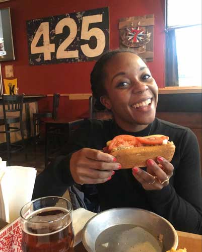 The author posing for a picture while holding a hotdog from The Red Hot