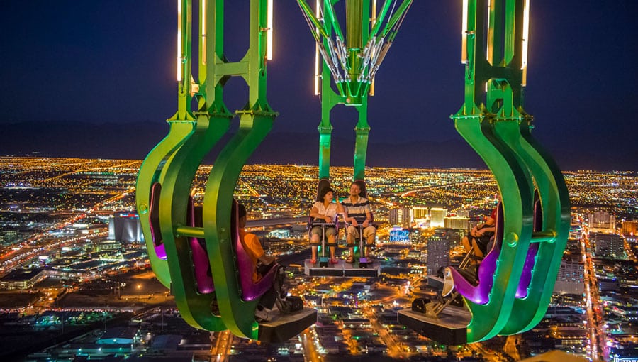 People on The X-Scream ride in the STRAT with the overlooking view of Las Vegas