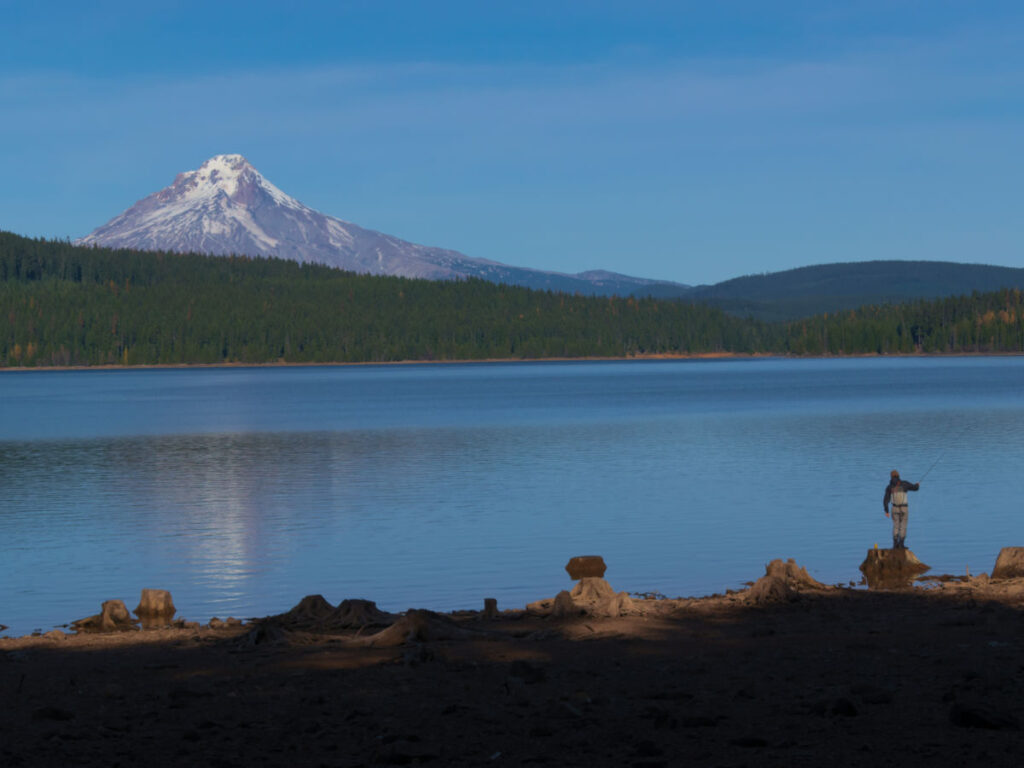 A man fishing at Timothy Lake with a view of Mt. Hood
