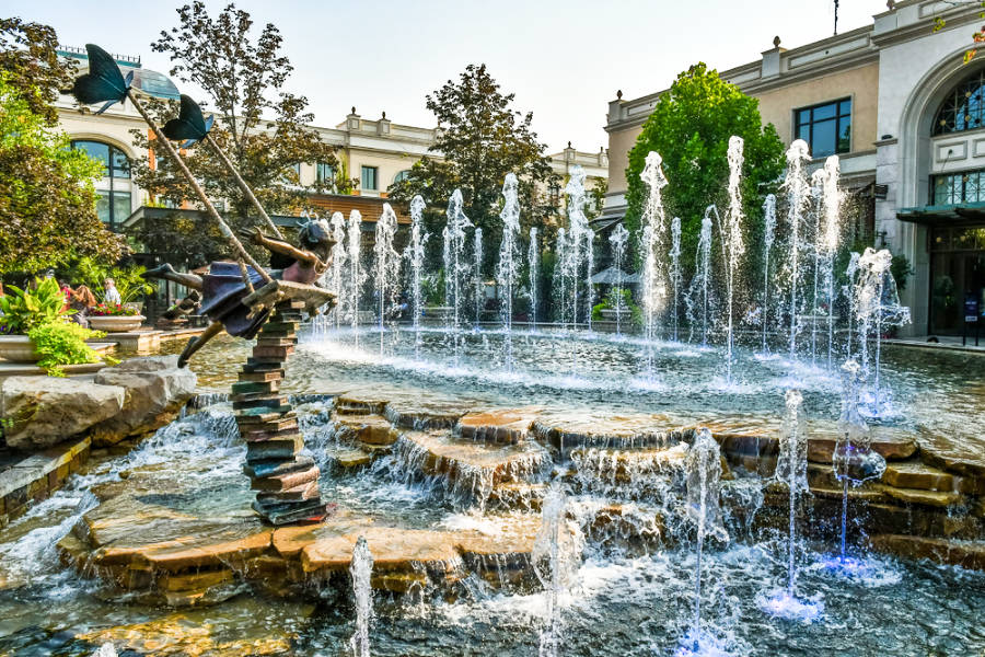 A large fountain with a statue of a girl in the stack of books at The Village shopping center