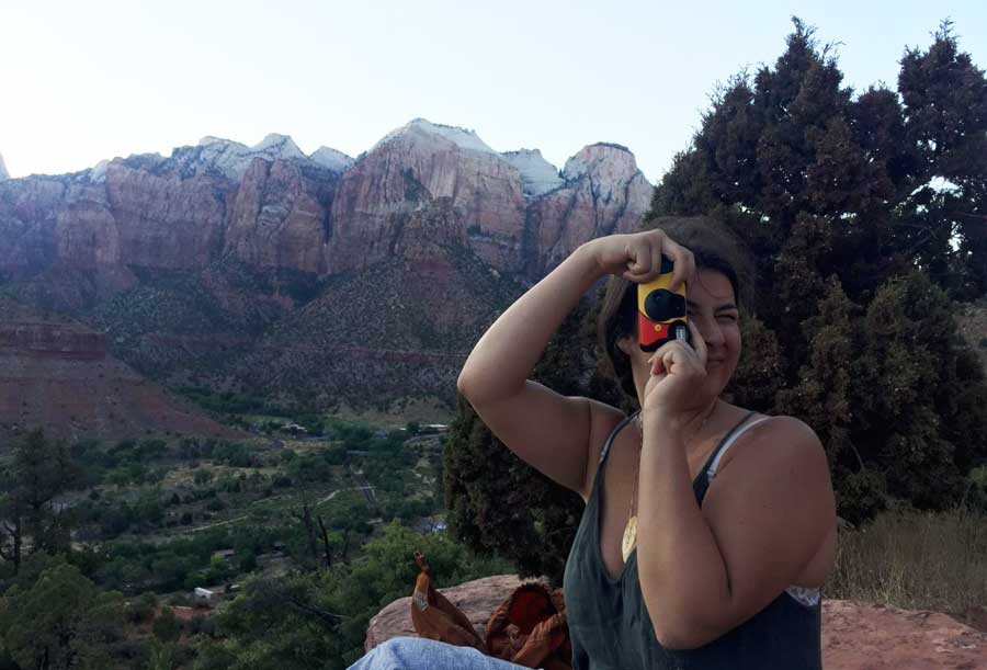View of a woman holding a camera to take pictures in The Watchman Trail