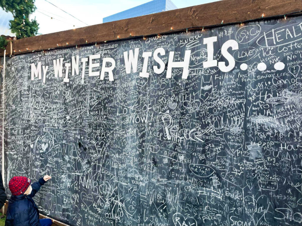 A child writing on the The Winter Wall of Wishes