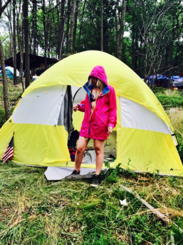 The author wearing a red coat near her yellow camping tent