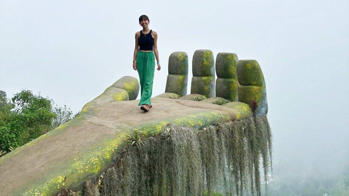 The author Lea Rose Allbaugh, posing at the Hobbitenango Guatemala Hand Statue, one of the best things to do in Antigua