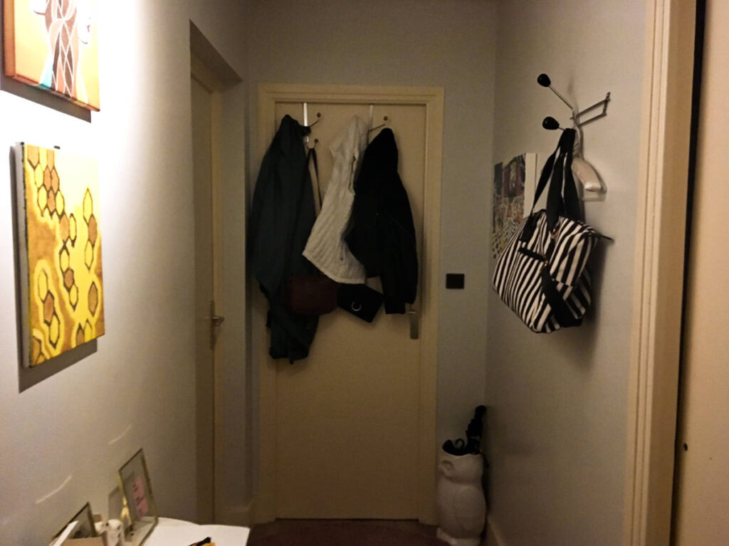The clothes hanging on the door with other two more doors, paintings and rack around the entryway