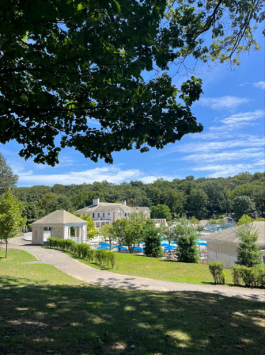 View of the aquatic center surrounded by greenery and clear blue sky in Tibbetts Brook Park
