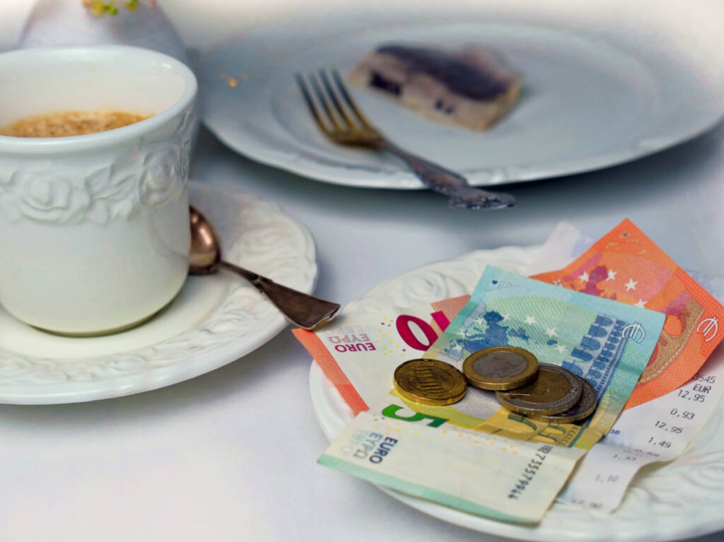 View of the empty plate, a cup of coffee, euro bills and coins on the table