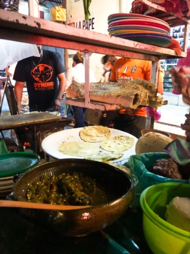 A street vendor making Tlayuda on a stand
