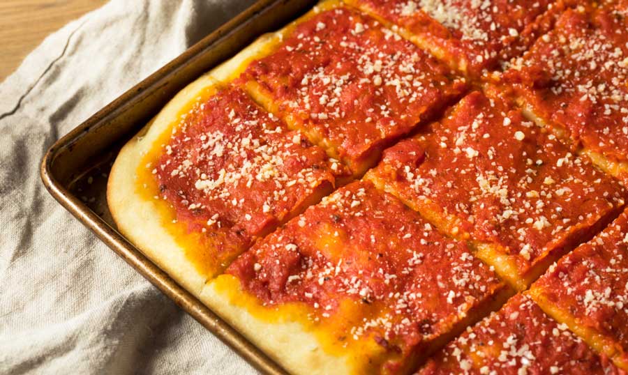 A freshly cooked tomato pie with grated cheese on a tray