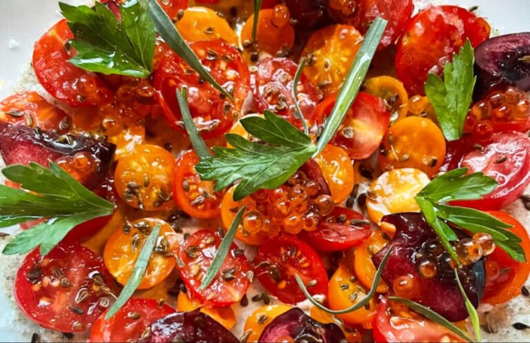 A dish of seasoned sliced tomatoes topped with herbs