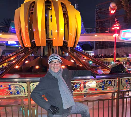 The author's father posing for a photo and the Tomorrowland’s Astro Orbiter Ride on his background