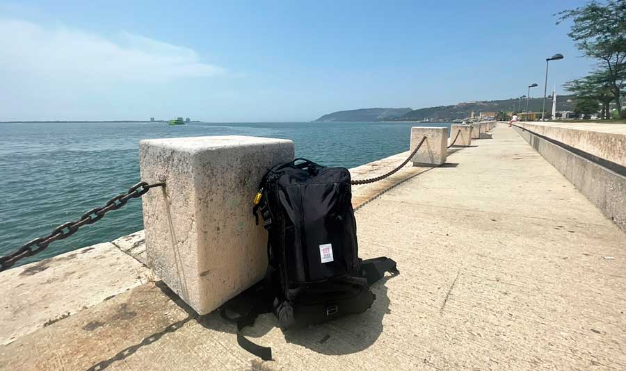 The Topo Designs Global Travel Bag and an ocean on its background