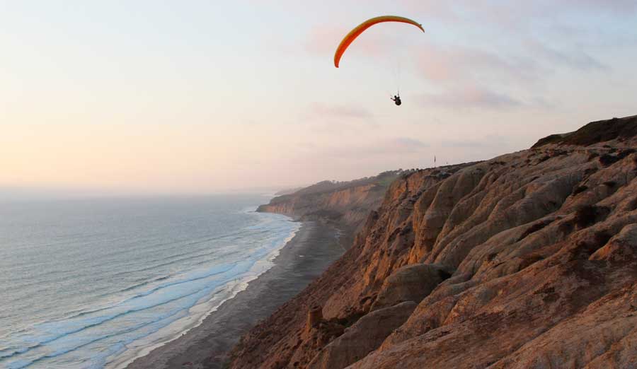 A man paragliding in Torrey Pines Gliderport at sunset