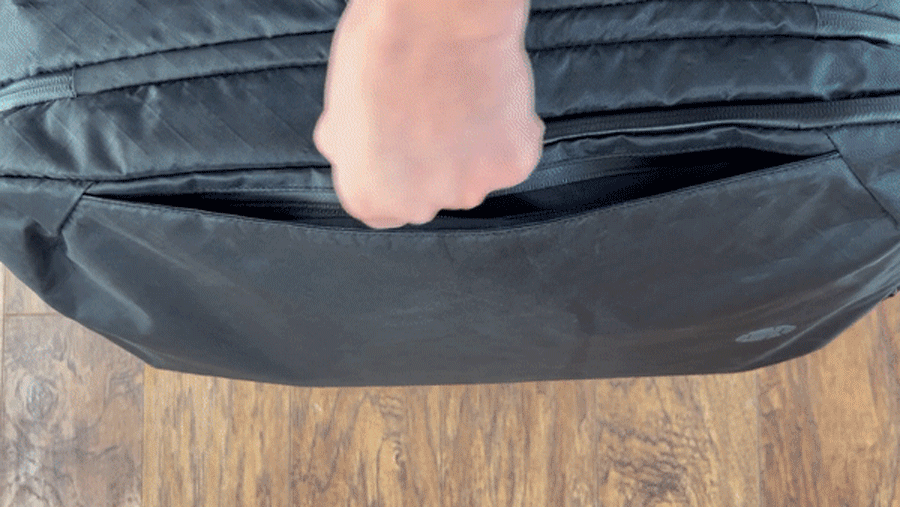 Abigail opening a zipper on the side of the Tortuga Travel Backpack