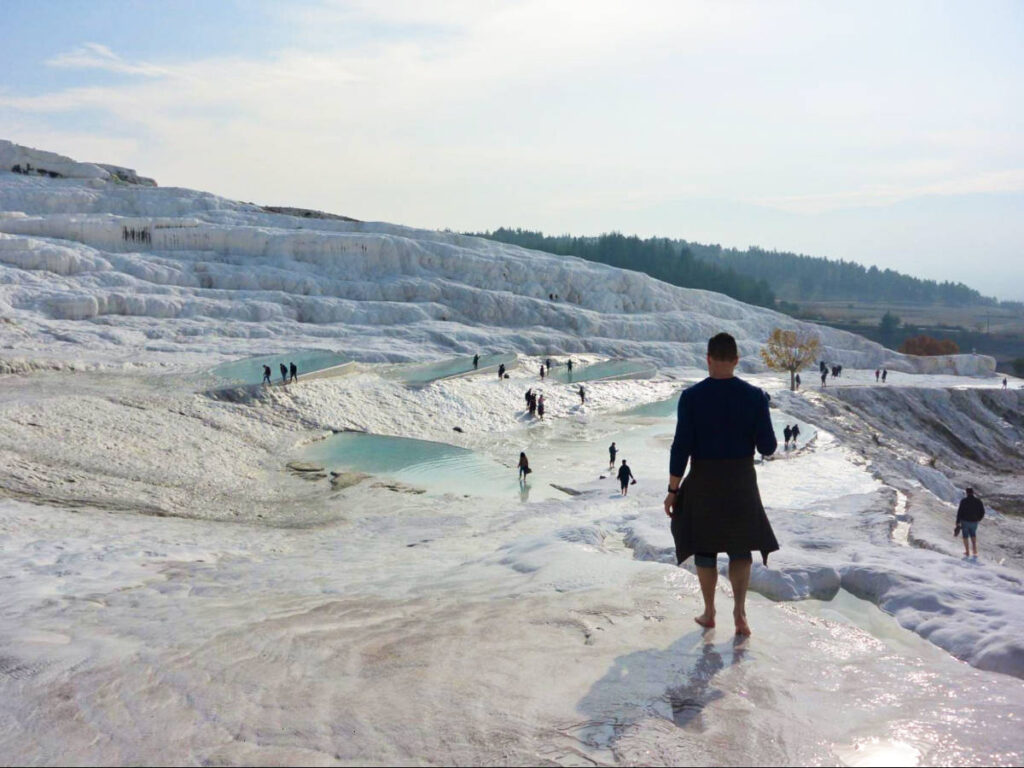 View of the people wandering around the Pamukkale travertine mineral formations in Türkiye