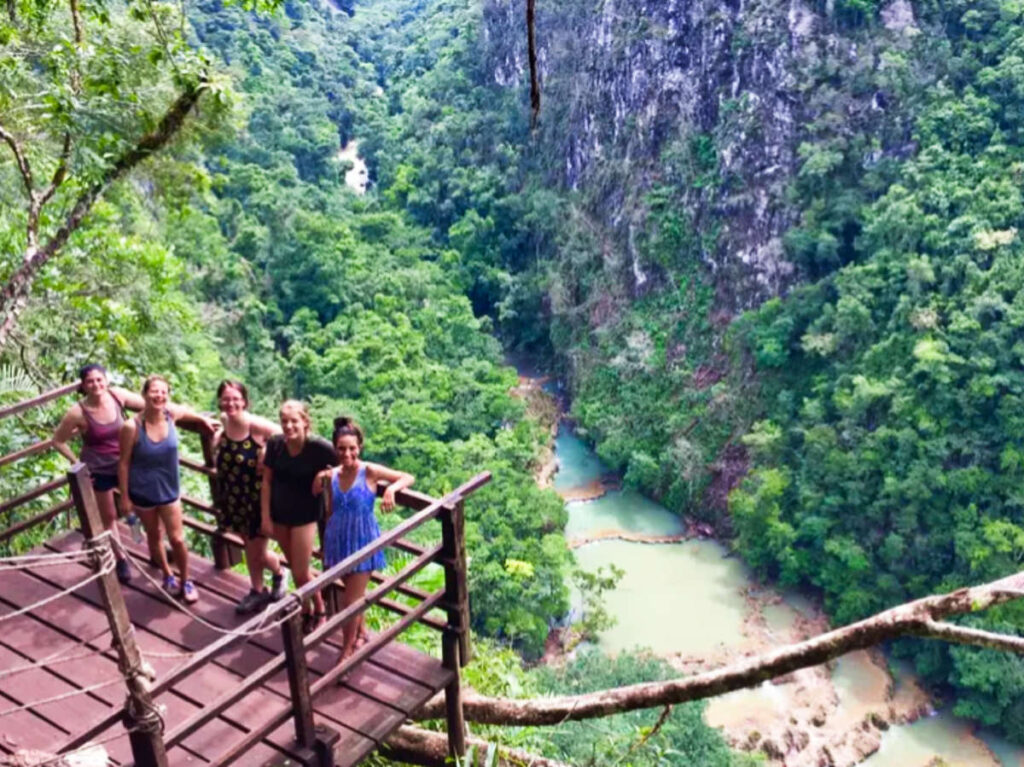 A group of friends posing for a photo with an overlooking view of the river at Semuc Champey