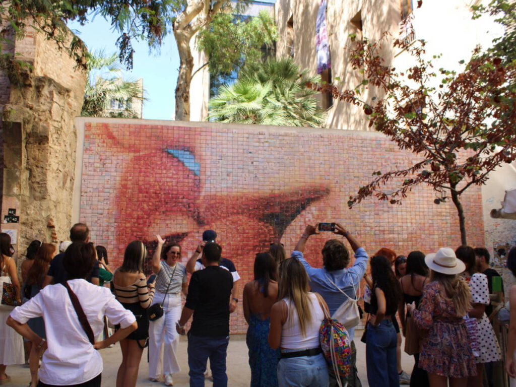 Tourists looking at the “The World Begins With Every Kiss” mural