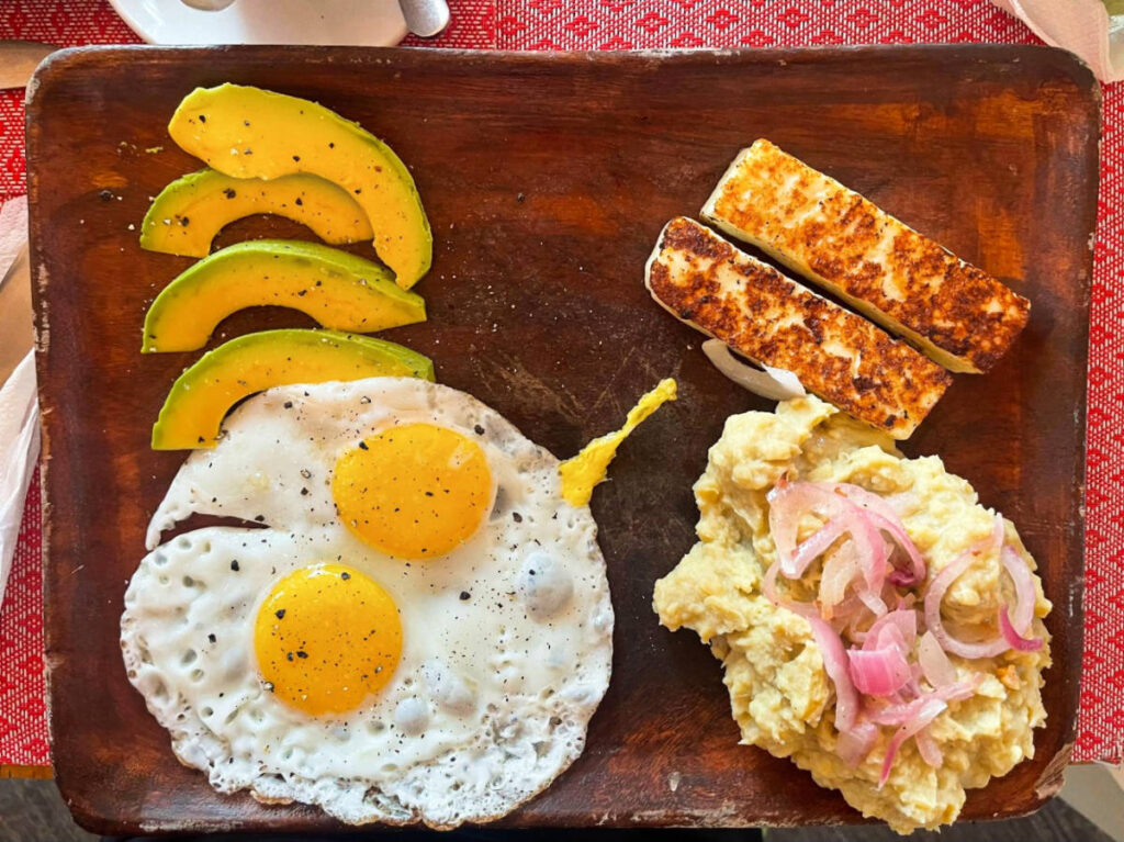 View of the traditional Dominican breakfast with eggs and sliced avocados on a wooden board