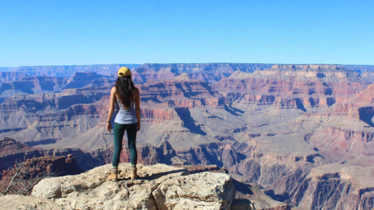 Travel Lemming author Abigail standing on a cliff admiring the views of Grand Canyon