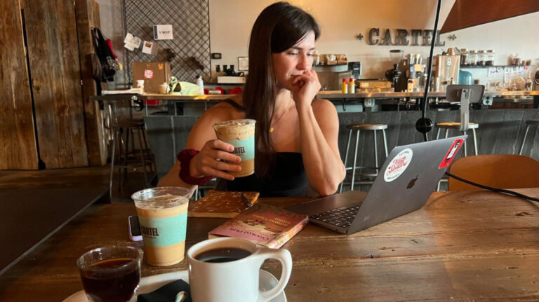 Travel Lemming author Betty enjoying her coffee while looking at her laptop at Cartel Coffee Lab