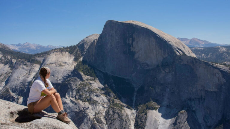 Travel Lemming author Laura sitting on a rock while looking at the Half Dome