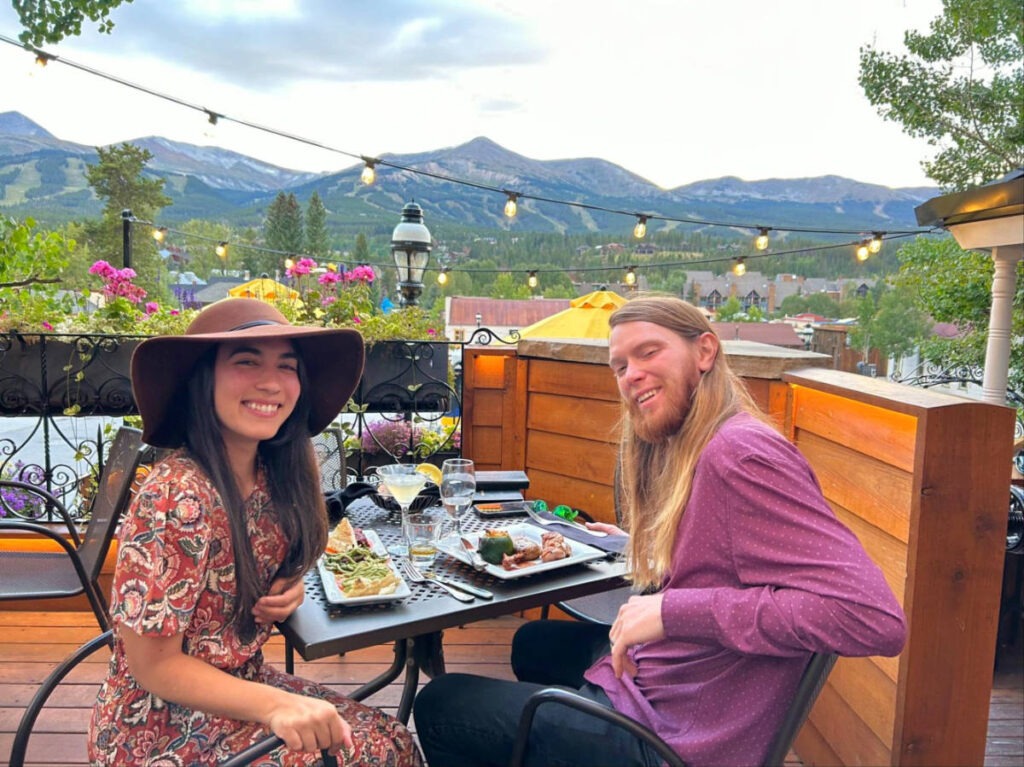 Travel Lemming editor Abigail and her husband enjoying dinner with mountains in the background in Breckenridge