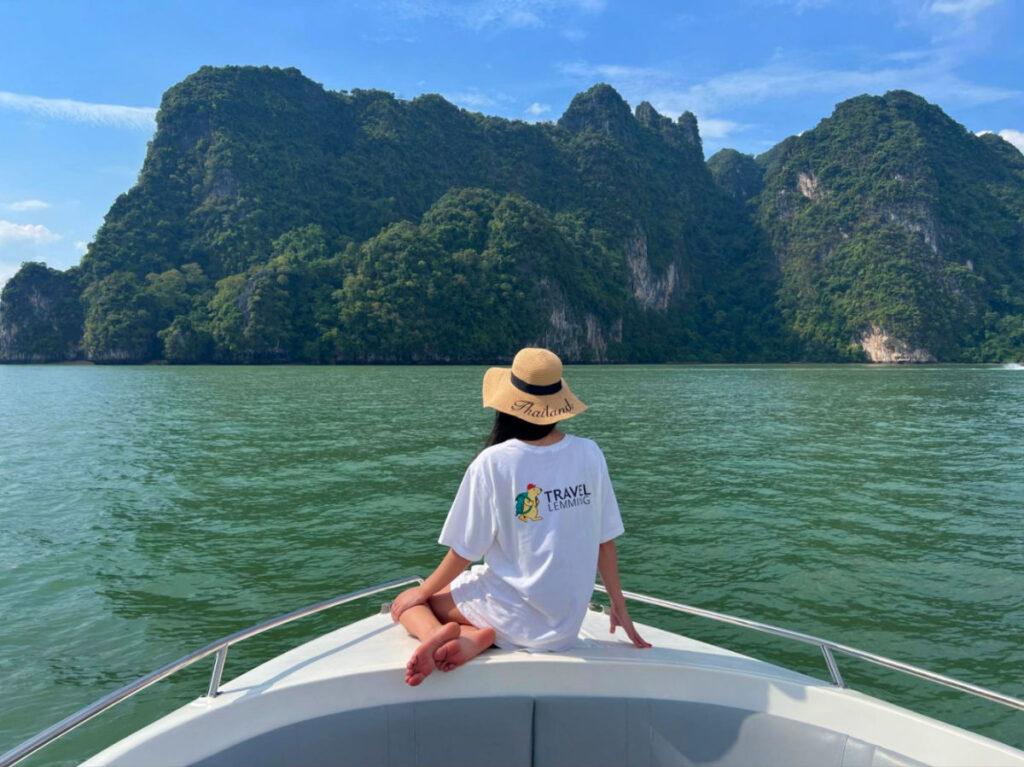 Travel Lemming writer Clara in a white shirt and hat sitting on the front of a boat during a tour near Phuket