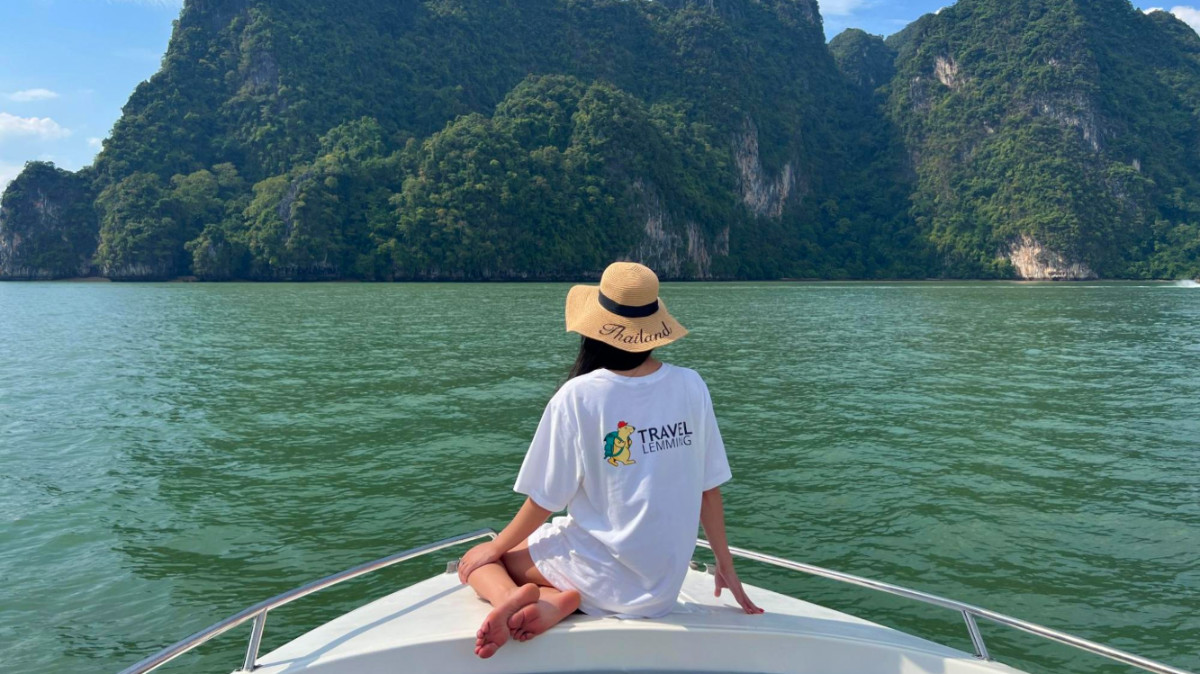 Travel Lemming writer Clara in a white shirt and hat sitting on the front of a boat during a tour near Phuket