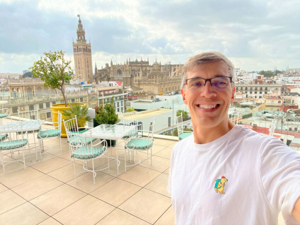 Travel Lemming founder Nate on the rooftop of Querencia de Sevilla with the cityscape view behind him