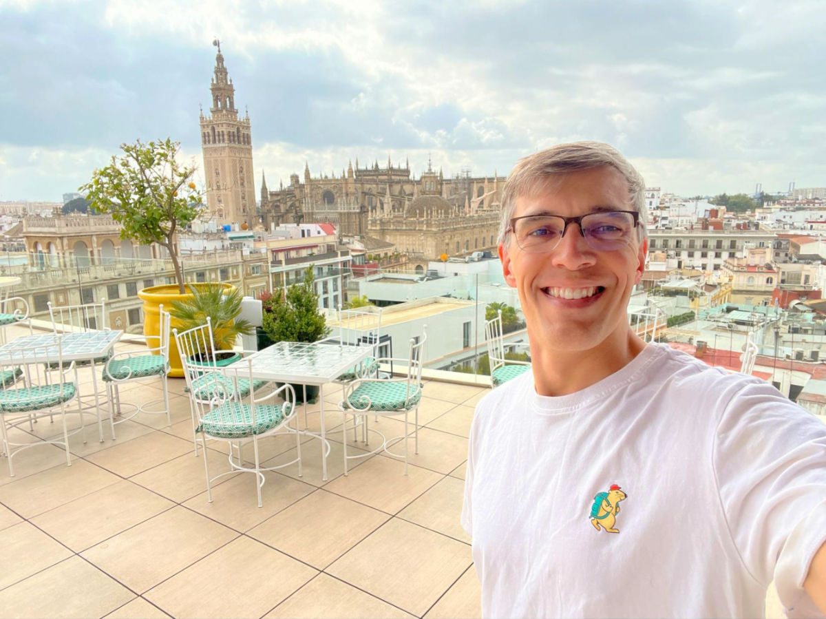 Travel Lemming founder Nate on the rooftop of Querencia de Sevilla with the cityscape view behind him