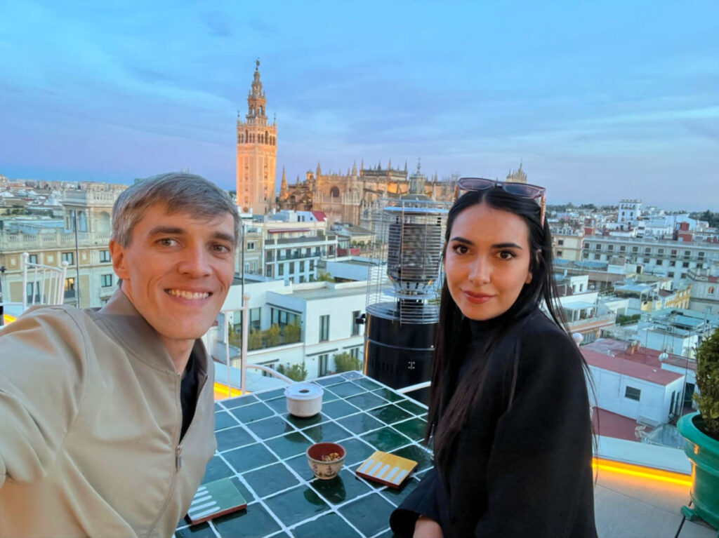 Travel Lemming writers Nate and Clara wearing light jackets on a rooftop in Seville