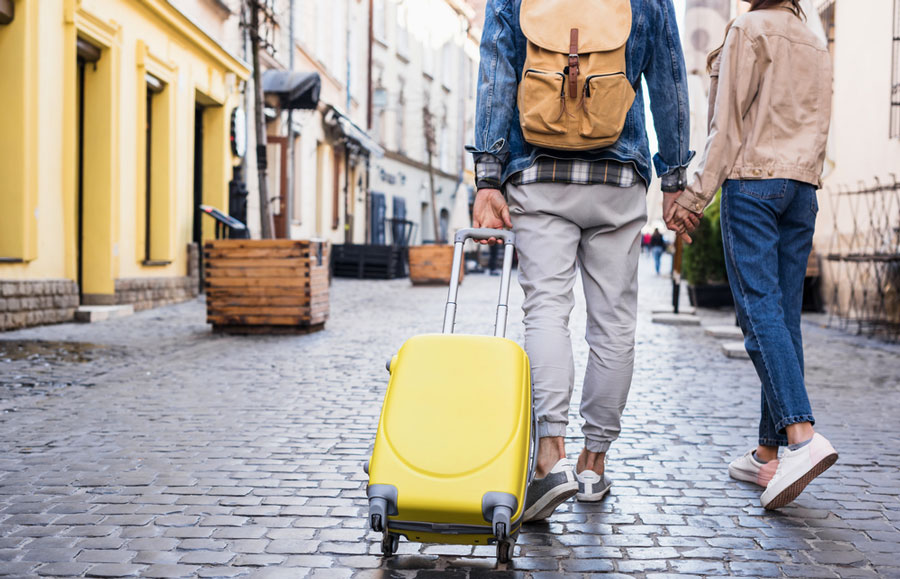 A traveler couple holding hands while walking on a street