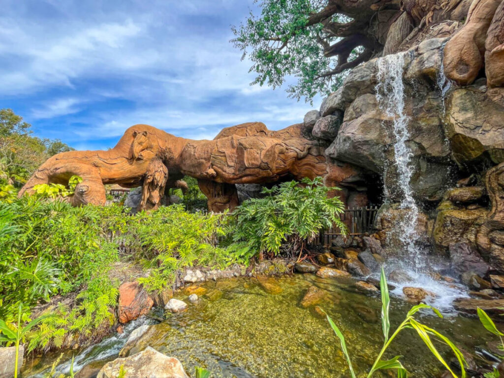 Waterfall at Animal Kingdom, surrounded by rocks, with the iconic Tree of Life in the background