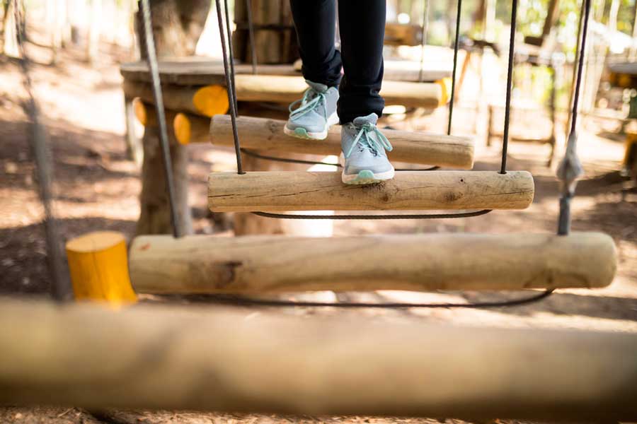 Close up view of a kid's shoe crossing a course in Treetop Adventure Park