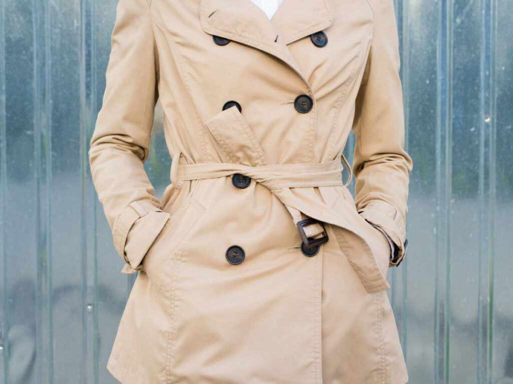 A woman wearing a trench coat with hands on the side pocket