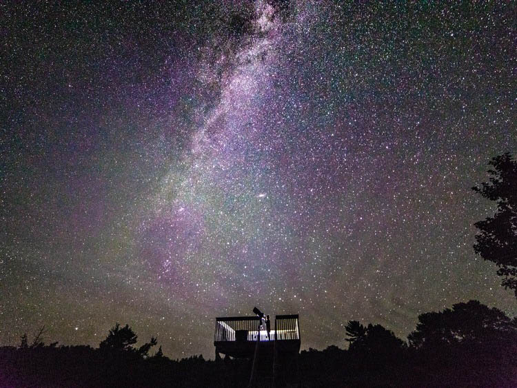 Person watching many stars at night with big telescope at Trout Point Lodge Nova Scotia