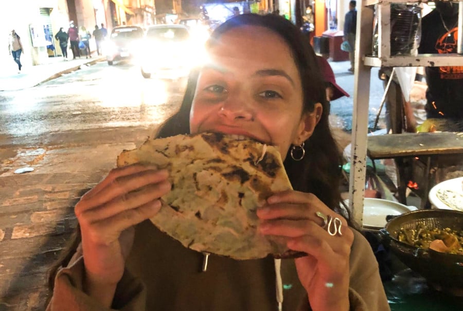 The author McKenna Mobley taking a bite of Tylayuda in the street of Oaxaca