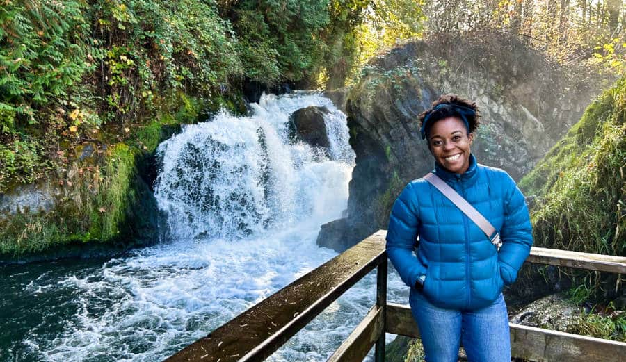 The author Chelsea Booker posing at the viewing deck with the Tumwater Falls in the background